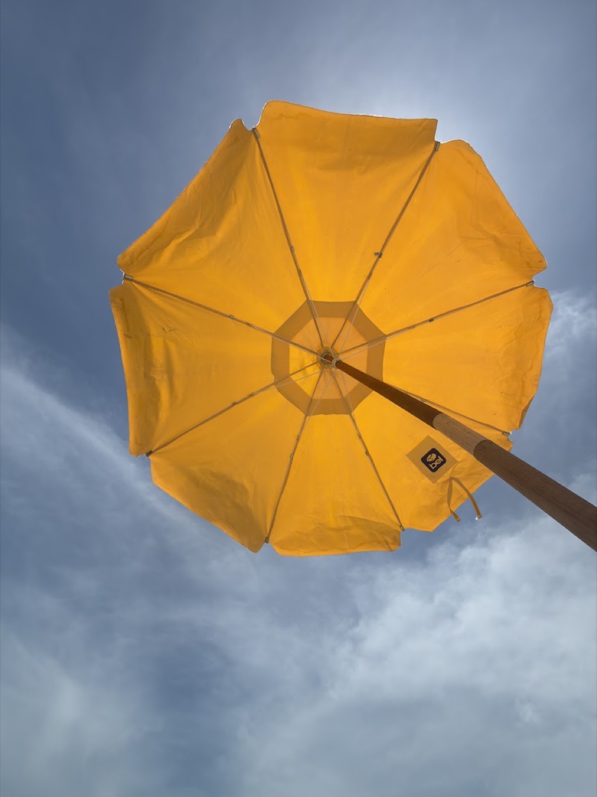 Guarda-sol amarelo visto de baixo em um dia de praia